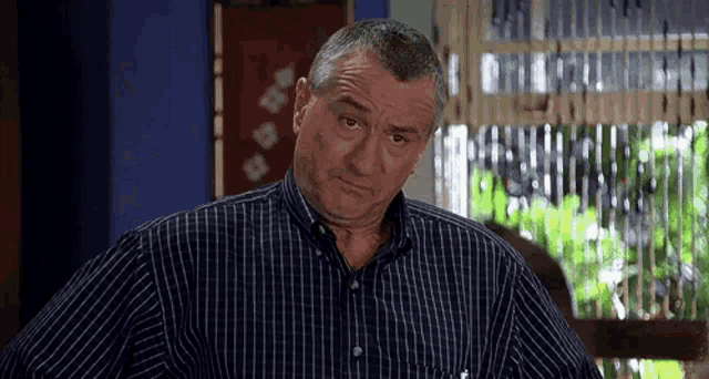 a man in a blue and white striped shirt is looking at the camera .