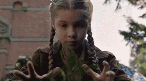 a young girl with pigtails is holding something in her hands .