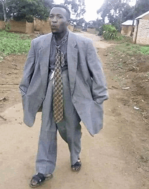 a man in a suit and tie is standing on a dirt road
