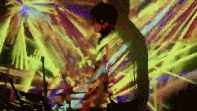 a man is playing drums in front of a colorful wall .