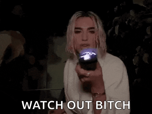 a woman is holding a flashlight in her hand in the dark and says `` watch out bitch '' .