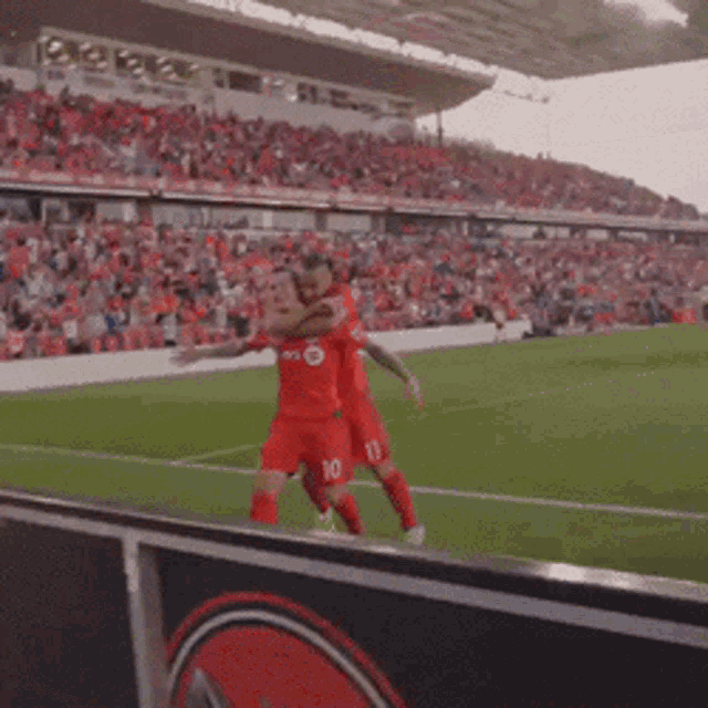 two soccer players wearing red jerseys with the numbers 10 and 11 hugging each other