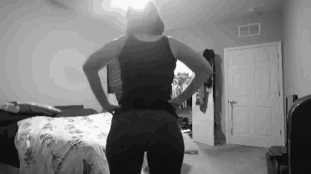 a black and white photo of a woman standing in a bedroom