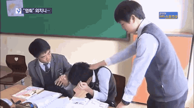 a group of boys are in a classroom with a kbc logo on the bottom right