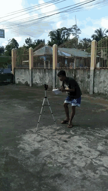 a man wearing blue shorts with the number 16 on them stands in front of a tripod