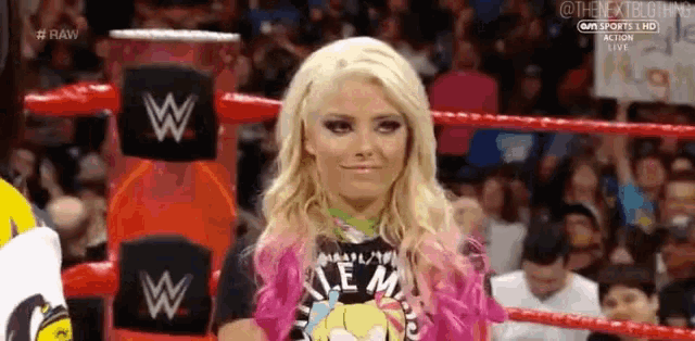 a woman is standing in a wrestling ring wearing a pink jacket and a black shirt .