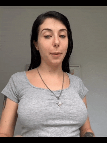 a woman wearing a grey t-shirt and a necklace with a cross on it