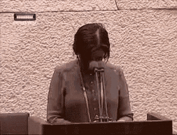a woman is standing at a podium giving a speech in front of two microphones .