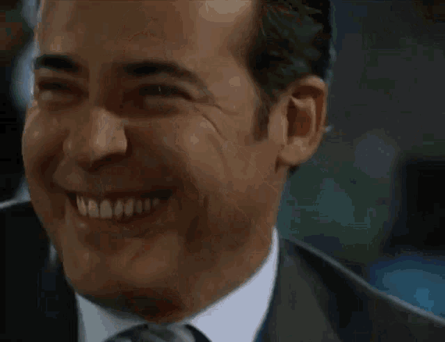 a man wearing a suit and tie is smiling