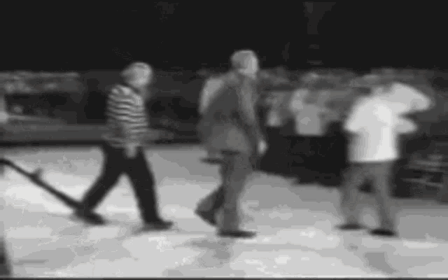 a black and white photo of a group of people walking on a snowy surface .