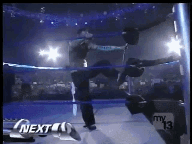 a man is standing in a wrestling ring next to a sign that says next on it