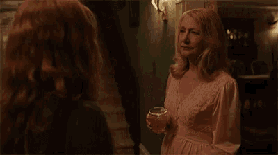 a woman in a pink dress is holding a glass of wine while standing next to another woman .