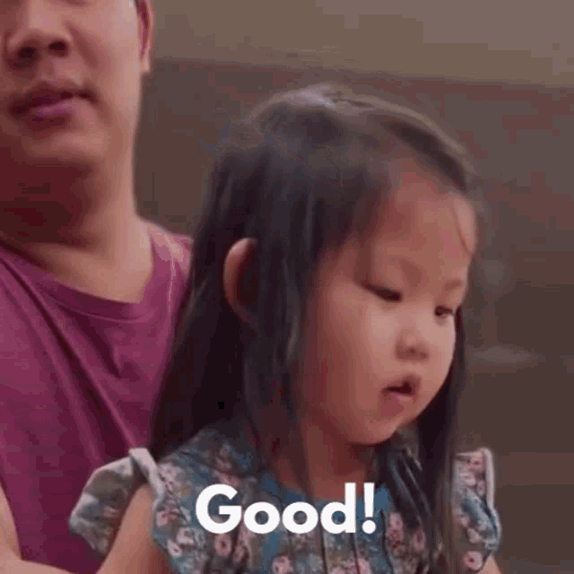 a little girl is giving a thumbs up while being held by her father .