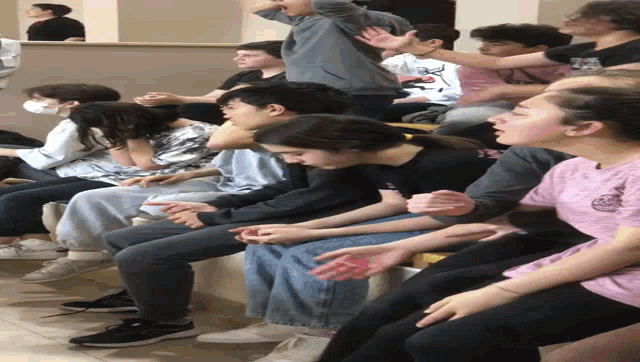 a group of people sitting in a row with one girl wearing a shirt that says ' abercrombie '