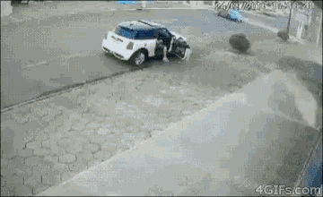 a blue car is crashing into a white car on the side of the road .