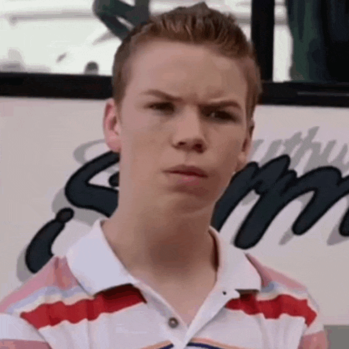a young man in a striped shirt is making a funny face in front of a bus .