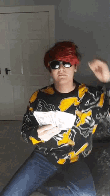 a man with red hair and sunglasses is holding a bunch of money in his hand