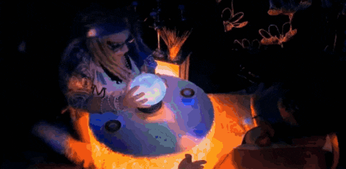 a woman is sitting at a table holding a crystal ball