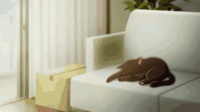 a cat is sleeping on a white couch next to a yellow box