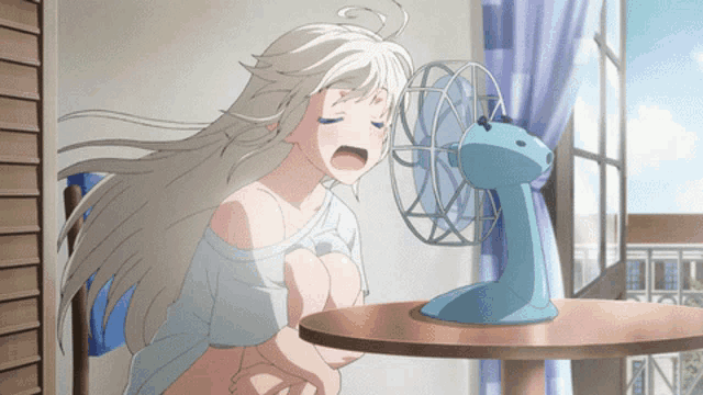 a girl is sitting at a table with a fan in front of her