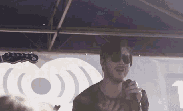 a man singing into a microphone in front of a banner that says iheartradio