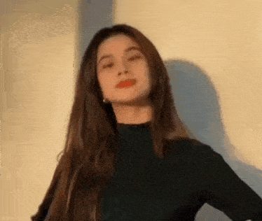 a woman with long hair is wearing a black turtleneck sweater and looking at the camera .