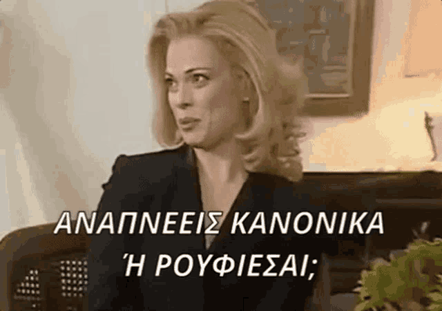 a woman in a black suit is sitting on a couch in a living room with the words anapneis kanonika written above her