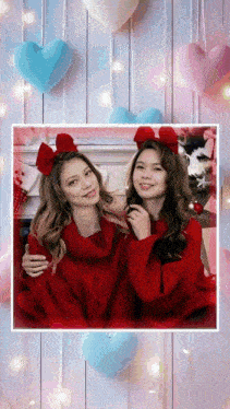 two girls wearing red sweaters with bows on their heads pose for a picture