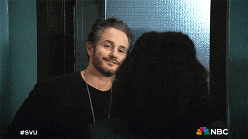 a man in a black shirt is looking at a woman in a doorway with the nbc logo on the bottom