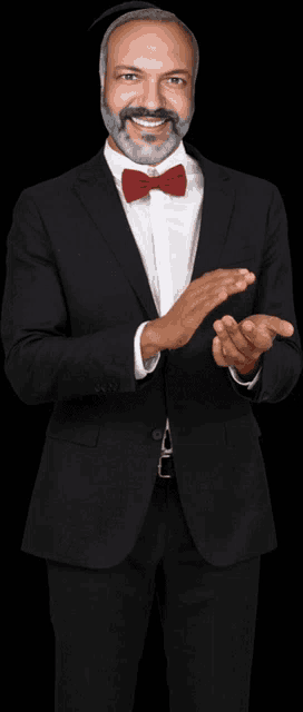 a man in a tuxedo and bow tie is clapping his hands
