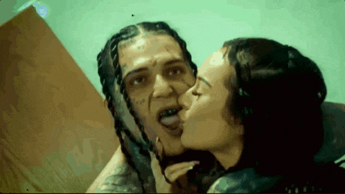 a woman is kissing a man on the cheek with his tongue out