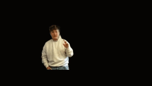 a young boy wearing a white sweater and blue jeans stands in front of a black background