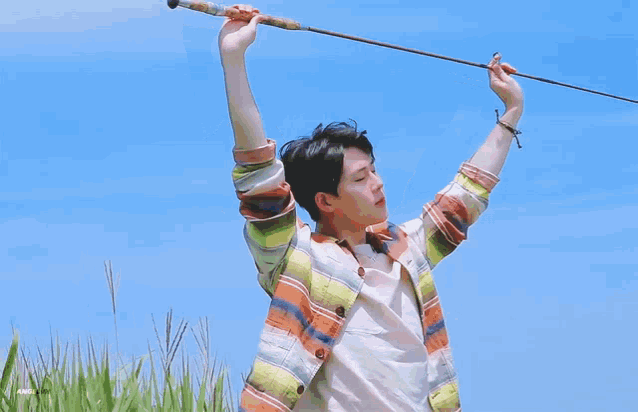 a young man is holding a fishing rod over his head in the air .