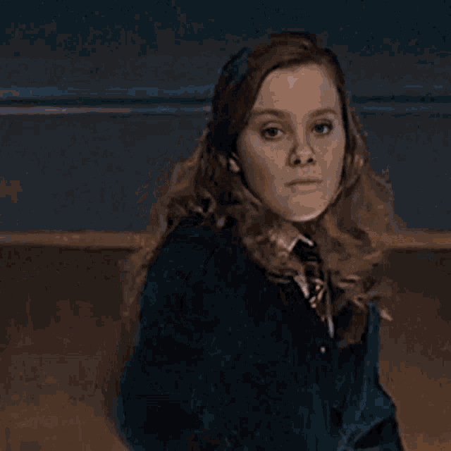 a woman in a school uniform is holding a wand that is glowing in the dark .
