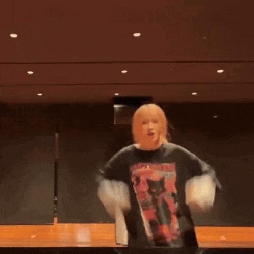 a woman is standing on a stage with her arms outstretched and a cat on her shirt .
