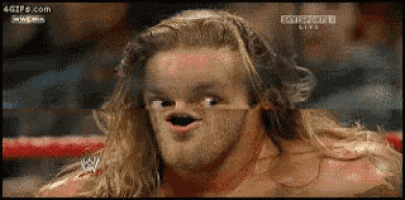 a wrestler is making a funny face in a wrestling ring .