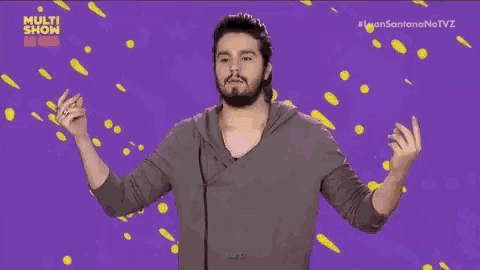 a man with a beard is standing in front of a purple background with the words multi show on it .