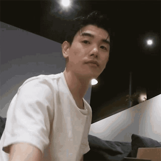 a man in a white shirt is sitting on a couch and looking at the camera