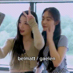 two women are standing next to each other in front of a window and making peace signs .
