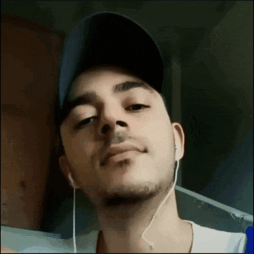 a man wearing a hat and ear buds is smiling for the camera