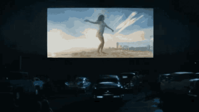 a movie screen shows a woman in a white dress standing on the beach