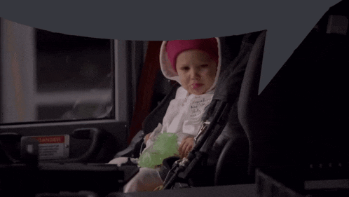 a baby wearing a pink headband is sitting in a car seat with a name tag that says " natasha "