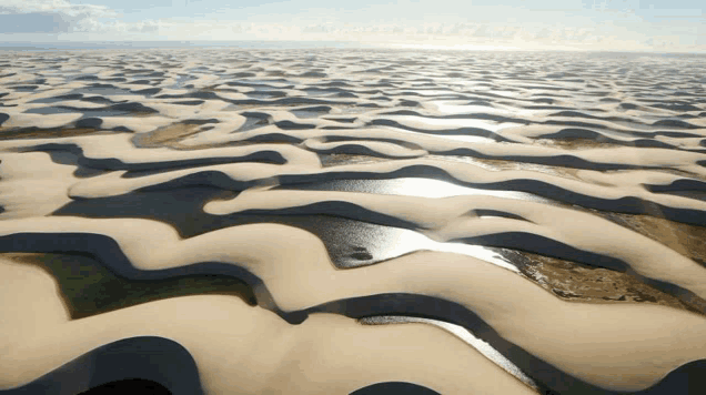an aerial view of a desert landscape with waves and water