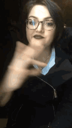 a woman wearing glasses and a blue shirt is making a funny face