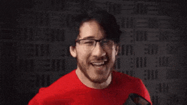 a man in a red shirt and glasses is making a funny face while making a funny face .