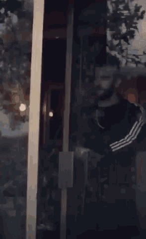 a man with a beard and a chain around his neck is standing in front of a door .