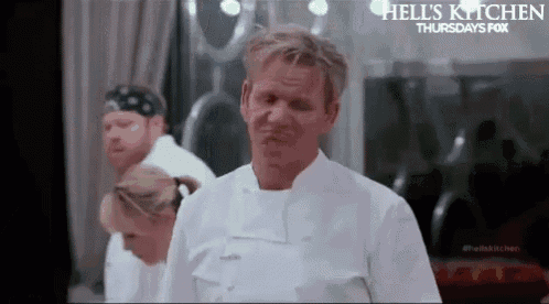 a man in a chef 's uniform is making a funny face in front of a group of chefs .