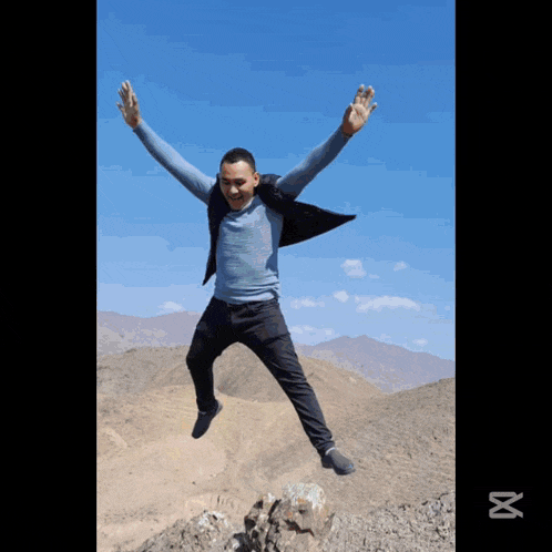 a man in a blue shirt is jumping in the air with his arms outstretched