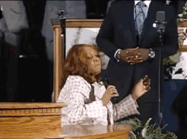 a woman singing into a microphone with a man in a suit standing behind her