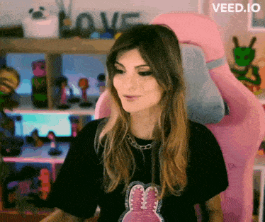 a woman sitting in a pink chair with a sign that says love in the background